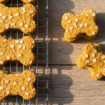 Pumpkin & Oat Dog Biscuits — An overhead shot of homemade pumpkin and oat dog biscuits arranged neatly on a cooling…