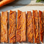 Dehydrated Turkey & Carrot Jerky Chews — An overhead shot of homemade dehydrated turkey and carrot jerky pieces arranged neatly…